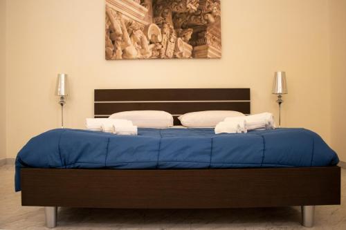 a bedroom with a blue bed with a painting on the wall at Apollo Suites in Lecce