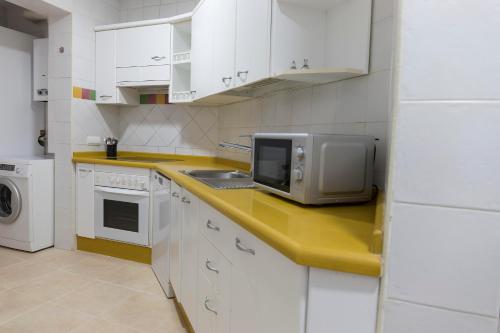una cocina con armarios blancos y microondas en una encimera en Titan, edificio Hipercor, con Parking, en Huelva