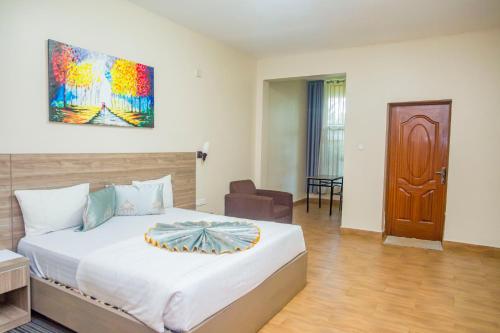 um quarto com uma cama e uma cadeira num quarto em Baobab Hotel LTD em Kigali