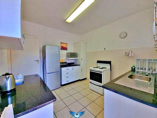 a kitchen with a refrigerator and a stove top oven at Fairway Holiday Accommodation in Hermanus