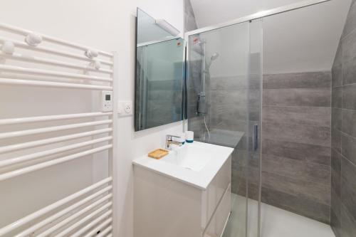 ein weißes Bad mit einem Waschbecken und einer Dusche in der Unterkunft AVEL VAEZ - Charmante maison à 2 pas de l'Aber Wrach in Landéda