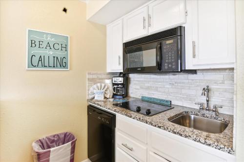 eine Küche mit einer Spüle und einer Mikrowelle in der Unterkunft Victorian 6106 - Seaside Suite in Galveston