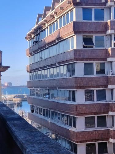 a building on the water next to the ocean at El Cielo de Fomento in Gijón