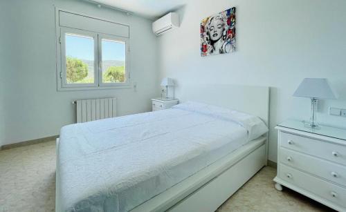 ein weißes Schlafzimmer mit einem Bett und einem Fenster in der Unterkunft Villa reina by costabravaway in Calonge