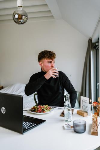 a man sitting at a table with a plate of food and a laptop at Uitgerust voor Zaken in Heerenveen