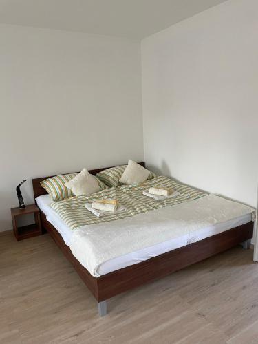 a bed in a bedroom with a white wall at AA Apartman - Kaposvár in Kaposvár