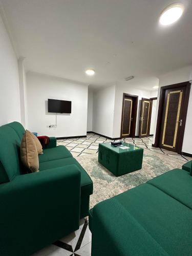 a living room with green furniture and a flat screen tv at AFAQ AL BATINAH - SAHAM in Şaḩam