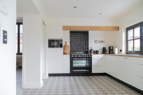 a kitchen with white cabinets and a stove at Vakantievilla Leonie in Lo-Reninge