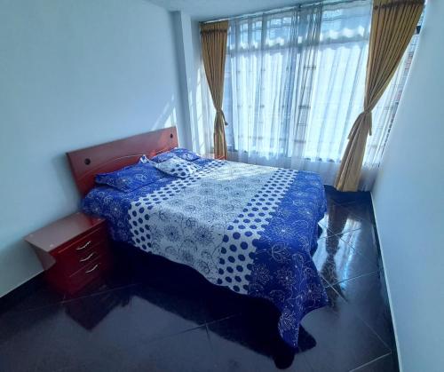 Un dormitorio con una cama azul y blanca y una ventana en Apartamento muy amplio, Familiar cerca al Aeropuerto el Dorado, en Bogotá