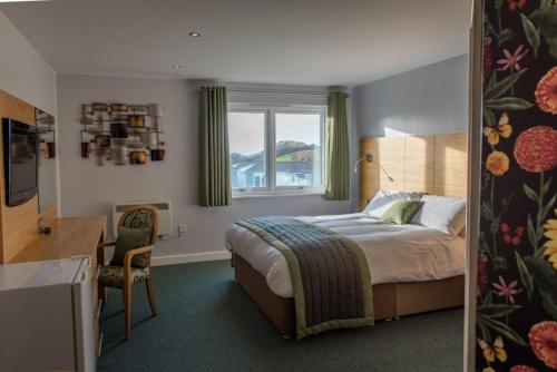a bedroom with a bed and a desk and a window at Croyde Bay Hotel or Self Catering in Croyde