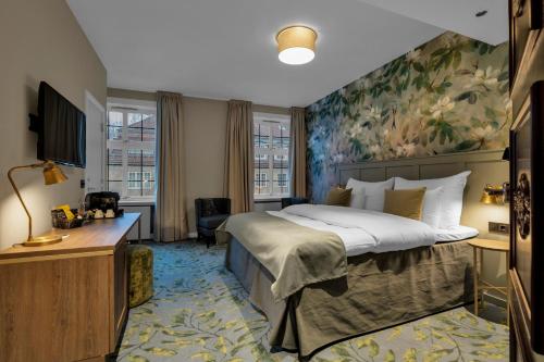 a bedroom with a large bed with a painting on the wall at Clarion Collection Hotel Gabelshus in Oslo