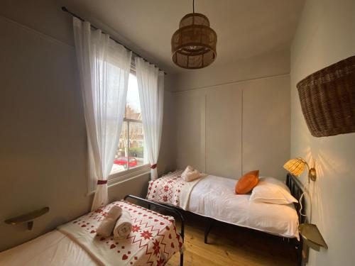 Duas camas num pequeno quarto com uma janela em Stylish Apt London Excel Olympic close to station em Londres