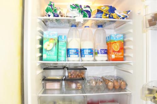 an open refrigerator filled with milk and other food items at Flexistay Aparthotel Sutton in Sutton
