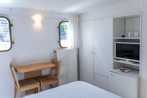 Habitación pequeña con cama, TV y cocina. en Hotel The Boatel, en Gante