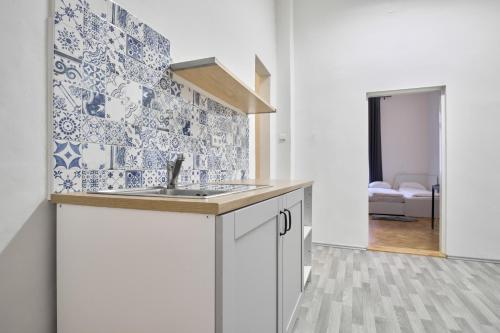 布拉格的住宿－Archibald Flats Prague，厨房配有水槽以及蓝色和白色的瓷砖
