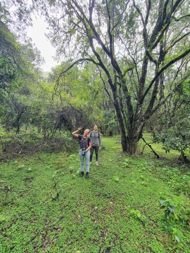a man and a woman standing in a field with a tree at Mazzola Safari House & Backpacking in Arusha