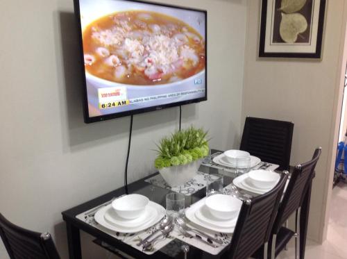 a dining room table with a television on a wall at Sea Residences MoA Manila in Manila