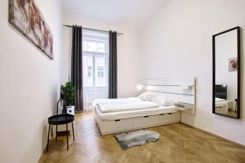 a white bedroom with a bed and a mirror at Archibald Flats Prague in Prague