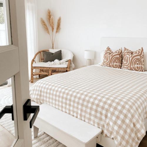 um quarto branco com uma cama e uma cadeira em The Hideaway - Guest House em Warrnambool