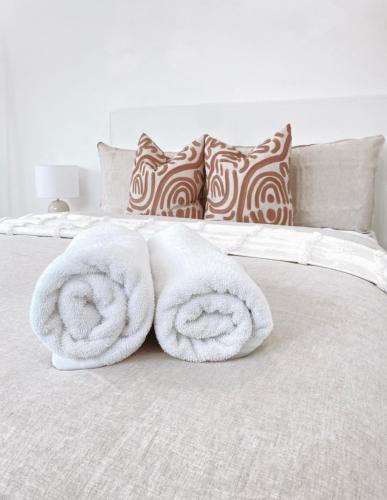 a white bed with two rolled towels on it at The Hideaway - Guest House in Warrnambool