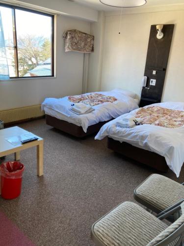 a room with two beds and a table and a chair at Resort Inn Seikan in Hakuba