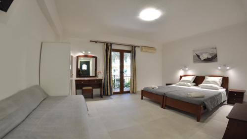a bedroom with a bed and a couch and a mirror at Villa Katerina Apartments in Liapades