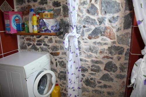 a bathroom with a washing machine and a stone wall at Blue Stone in Triopetra
