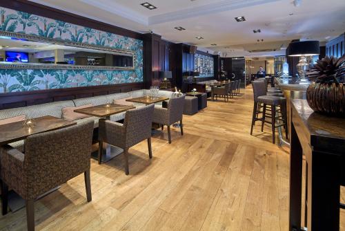 un restaurante con mesas y sillas y un bar en Mandolay Hotel Guildford en Guildford