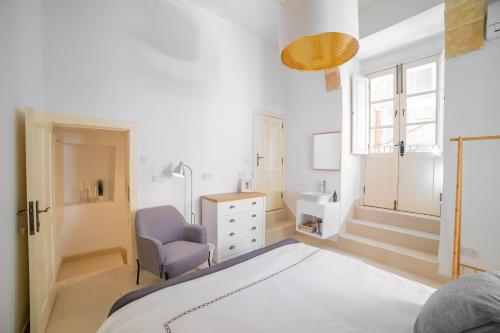 a bedroom with a bed and a chair and a sink at Carmelita Maisonette Valletta in Valletta