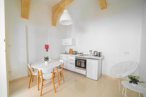a white kitchen with a table and chairs and a sink at Carmelita Maisonette Valletta in Valletta