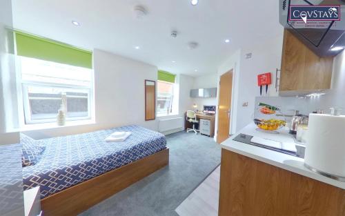a small room with a bed and a kitchen at Victoria House - Deluxe Studios in Coventry City Centre, free parking, by COVSTAYS in Coventry