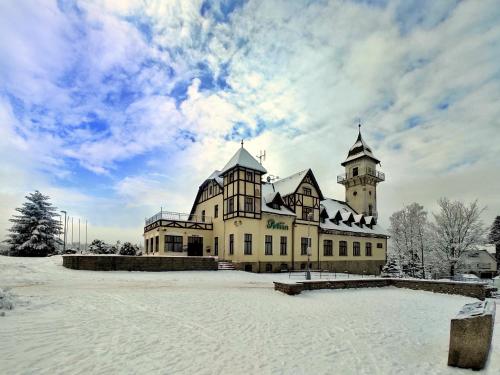 a large building with two towers in the snow at Hotel Petřín in Jablonec nad Nisou
