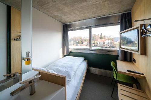 ムルテンにあるCentre Loewenbergのベッドと窓が備わる小さな客室です。