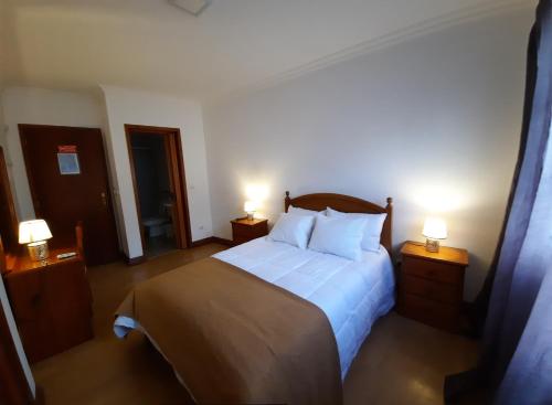 a bedroom with a large bed with two lamps at Hotel Insular in Ponta Delgada