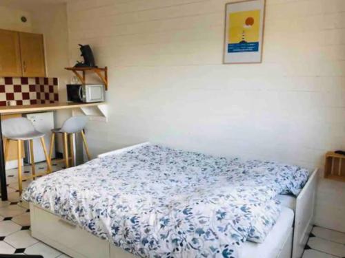 a bedroom with a bed with a blue and white blanket at Foch, proximité immédiate plage-port-commerces in Courseulles-sur-Mer