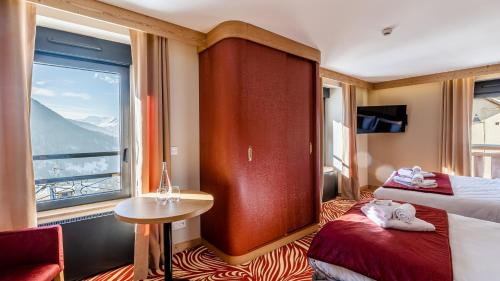 a hotel room with two beds and a window at Madame Vacances Hotel Les Cimes in Vaujany