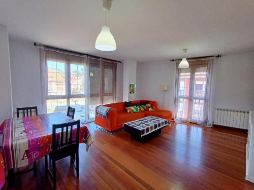 ein Wohnzimmer mit einem orangenen Sofa und einem Tisch in der Unterkunft Centro, garaje incluido, La casita de Nani, entre río y montañas wifi free in Ramales de la Victoria