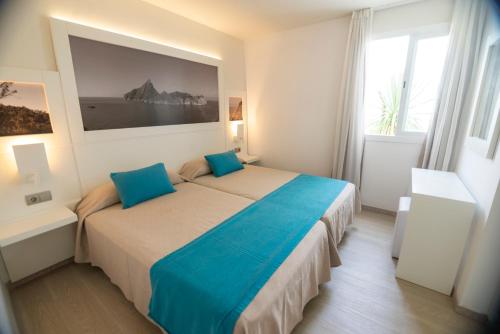 a bedroom with a large bed with blue pillows at Apartamentos Bora Bora - Adults Only in Playa d'en Bossa