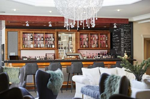 a restaurant with a bar with chairs and a chandelier at Hotel Rosenstock - Erwachsenenhotel - Adults only 15 plus in Fischen