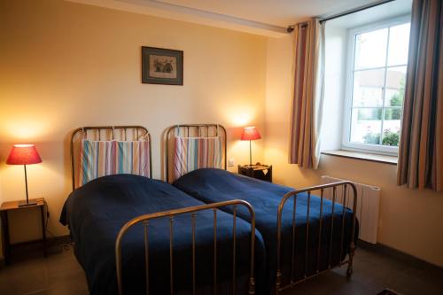 NormierにあるGite Le Villageのベッドルーム1室(青いシーツと窓付きのベッド2台付)