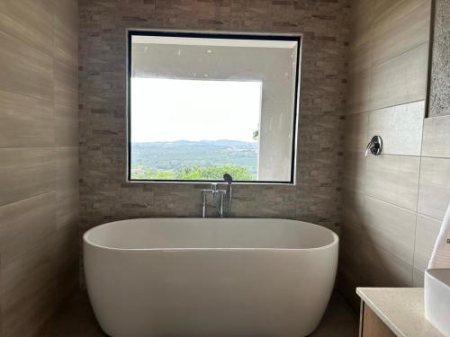 uma banheira branca na casa de banho com uma janela em Hazyview Accommodation, Bon Repose Cottages 3&4 em Hazyview