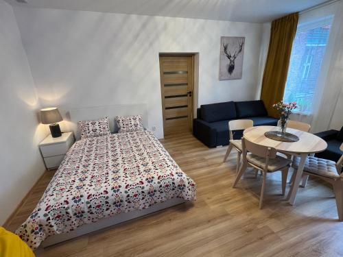 ein Schlafzimmer mit einem Bett, einem Tisch und einem Sofa in der Unterkunft Wood Apartment z Konsola X-Box in Kattowitz