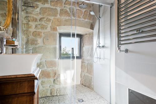 a stone bathroom with a shower and a sink at Catalunya Casas Fabulous Villa for 28 with Heated Pool in Torá de Rulbregos