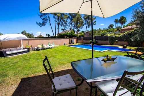 a table and chairs with an umbrella and a pool at Catalunya Casas Modern and spacious with private pool close to BCN in Senmanat