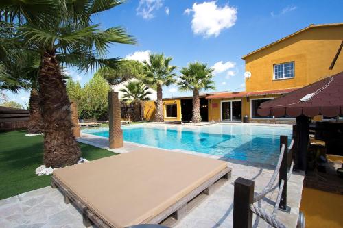 a swimming pool with a table and palm trees at Catalunya Casas Relax and Recharge - only 34km from Barcelona! in Rubí