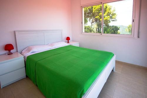 a white bedroom with a green bed and a window at Catalunya Casas Fun and Frolic in Lloret del Mar 3500 meters to beach! in Lloret de Mar