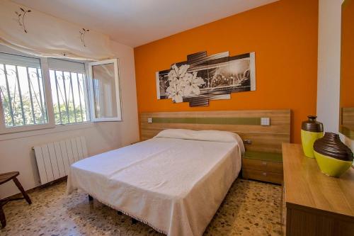 a bedroom with an orange wall with a bed and a desk at Catalunya Casas Beach Vibes Villa less than 1km to town and sea! in Hospitalet de l'Infant
