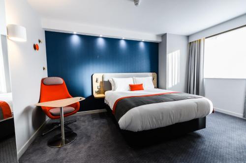 um quarto de hotel com uma cama e uma cadeira vermelha em Holiday Inn Express - Wigan, an IHG Hotel em Wigan