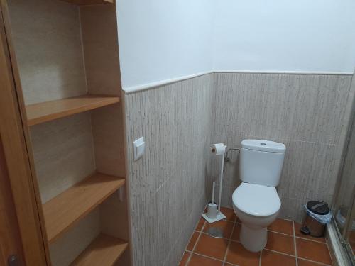 a small bathroom with a toilet and shelves at Casa Rural La Maestra in Ronda
