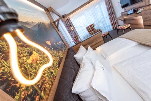 Schlafzimmer mit einem Bett mit Wandgemälde in der Unterkunft Hotel Tyrol in Oberstaufen